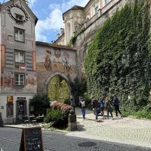 a group of people walking down a street next to a wall