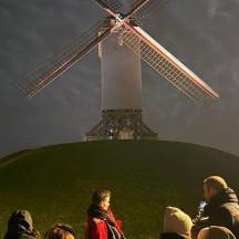 Un grupo de personas de pie frente a un molino de viento.