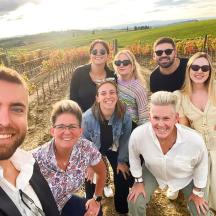 a group of people posing for a picture in a vineyard