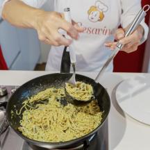a person cooking noodles in a pan on a stove