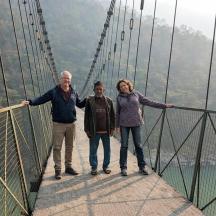 a group of three people standing on a suspension bridge