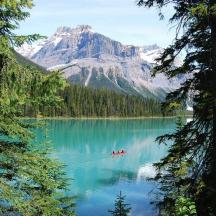 a couple of people in a boat on a lake with a mountain
