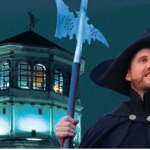 a man dressed as a wizard holding a flag in front of a tower