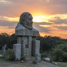 a statue of a head on aolith with a sunset in the background