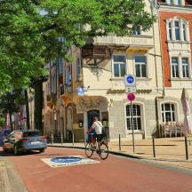 Ein Mann fährt mit dem Fahrrad eine Straße vor einem Gebäude entlang