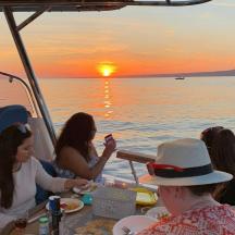 a group of people sitting at a table eating food on a boat