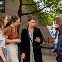 fire kvinder står rundt og kigger på en mobiltelefon