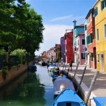 dalawang bangka ang nakadaong sa isang kanal na may mga makukulay na gusali