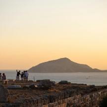 a group of people standing on a wall near the ocean
