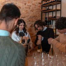 um grupo de pessoas em pé ao redor de uma mesa com garrafas de vinho