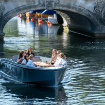 un grup de persones en una barca a l'aigua prop d'un pont