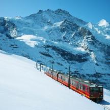 ein roter Zug, der einen schneebedeckten Berg hinunterfährt