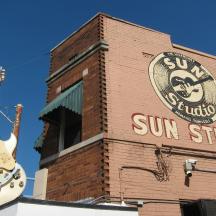 a guitar on the side of a building with a sun studio sign
