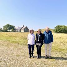 three people standing in a field with a house in the background