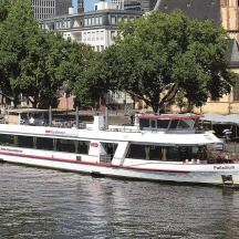 ein weißes Boot auf einem Fluss in einer Stadt