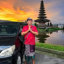 a man standing next to a car in front of a pagoda