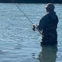 a man standing in the water holding a fishing rod