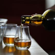 a person pouring alcohol into a glass on a table