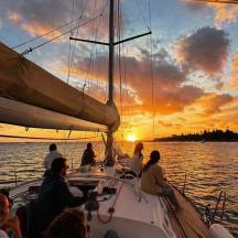 a group of people on a boat in the water at sunset