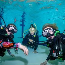 un gruppo di tre persone che indossano attrezzatura subacquea in acqua
