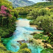 Un río en medio de un bosque con agua azul.