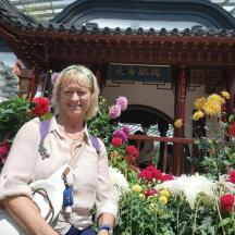 an older woman sitting in front of a display of flowers
