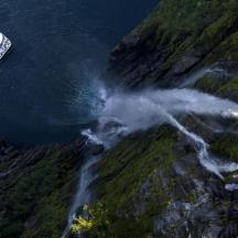 a boat in the water next to a waterfall