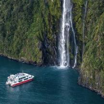 a boat in the water in front of a waterfall