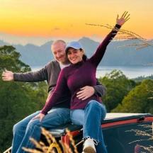a man and a woman sitting on the roof of a car