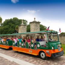 a group of people riding a green and orange trolley