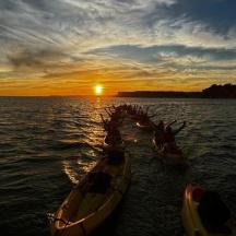 a group of boats in the water at sunset