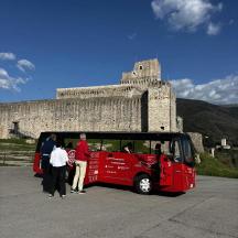 un grup de persones dempeus fora d'un autobús vermell