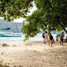 a group of people walking on a beach with a boat