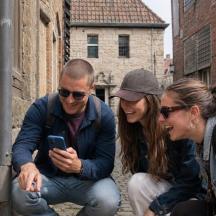 a group of three people looking at a cell phone