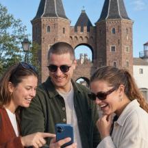 tre persone che guardano un cellulare davanti a un castello