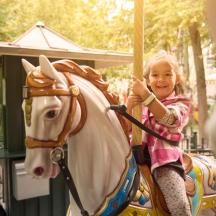 a little girl riding a horse on a carousel