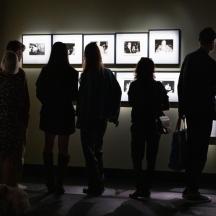 a group of people looking at photographs in an art exhibit