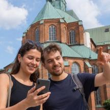 a man and woman standing in front of a building with a cell phone