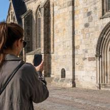 Eine Frau fotografiert ein Gebäude mit ihrem Handy.