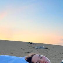 ผู้หญิงคนหนึ่งนอนอยู่บนชายหาดพร้อมกับ