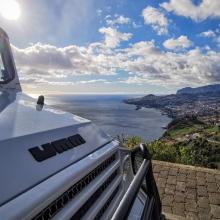 a white truck parked on top of a hill overlooking the ocean