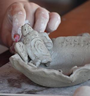 osoba robiąca glinianą miskę z jaszczurką na niej