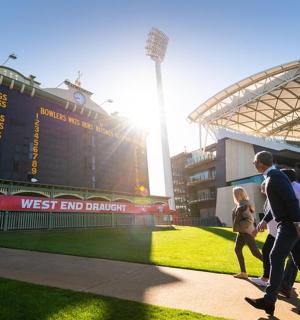 two people walking in front of a baseball stadium