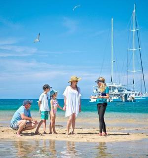 a group of people standing on a beach with a boat