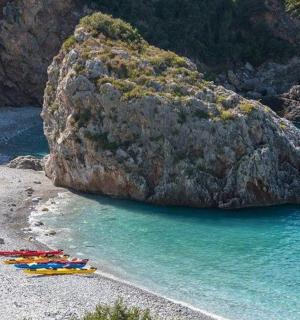 海滩上一块大石头旁边的一组遮阳伞