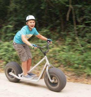 a young boy riding a scooter down a road