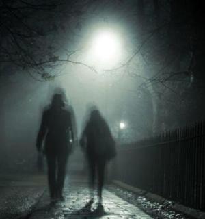 dva lidé jdoucí v noci po ulici