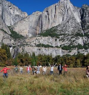 a group of people in a field in front of a mountain