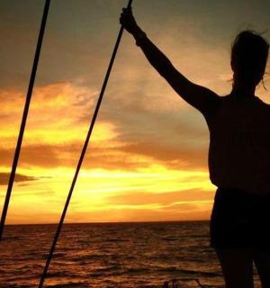 a woman standing on a boat at sunset