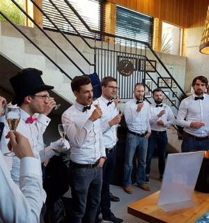 a group of men standing at a bar drinking wine